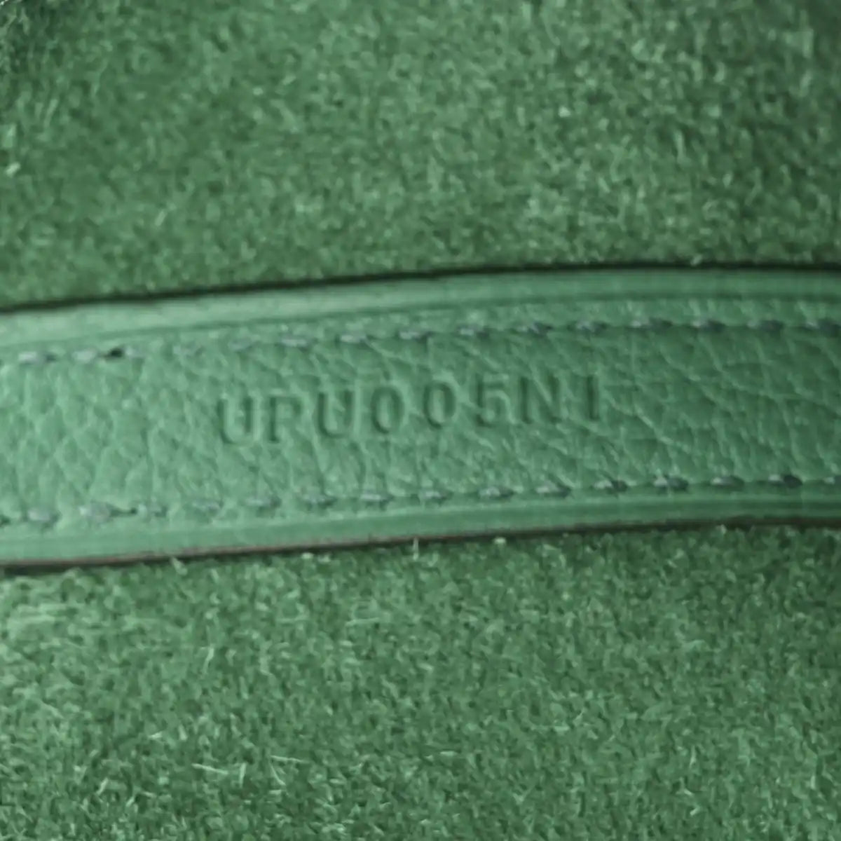 Close-up of green leather trim with embossed serial-style text