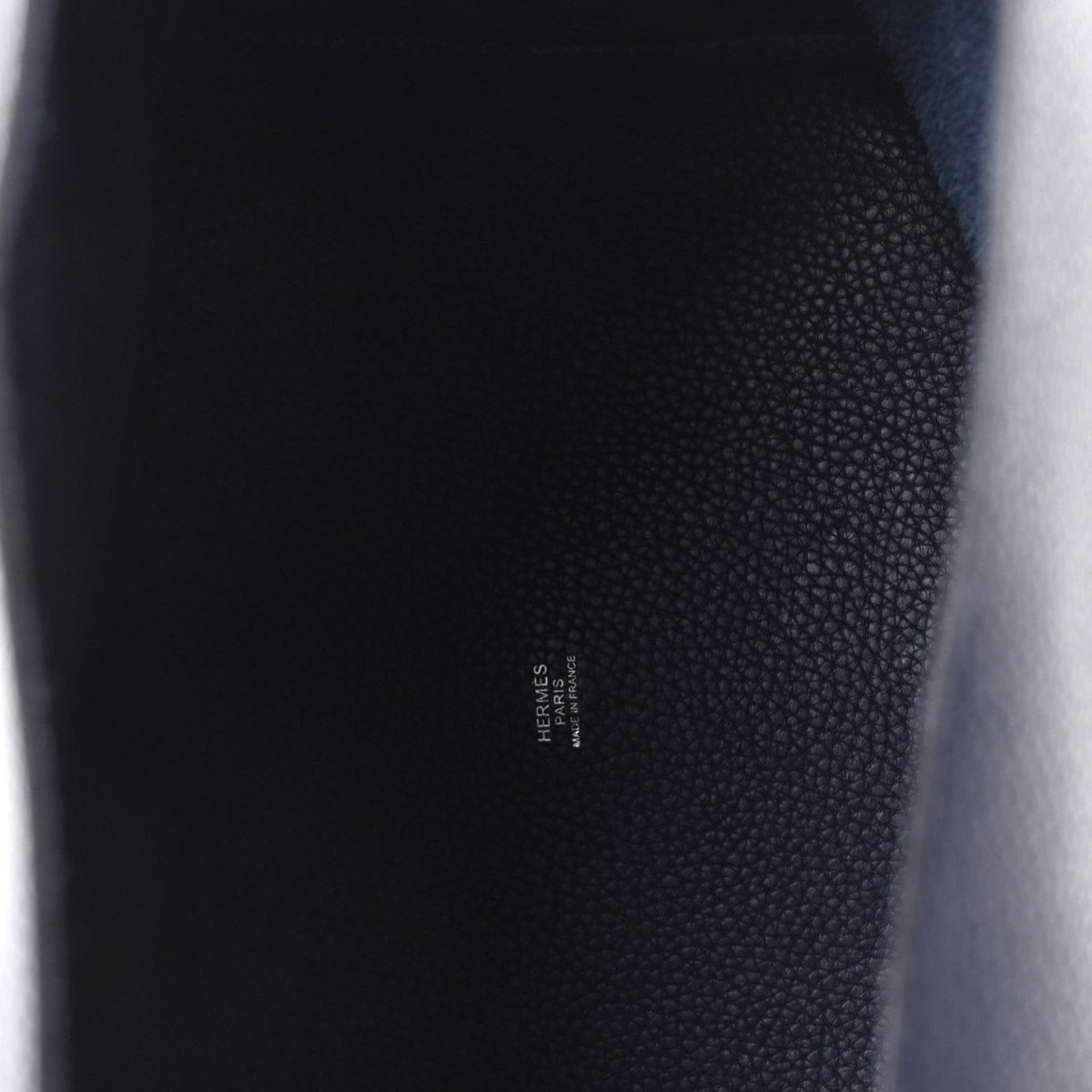 Close-up of textured navy leather with small embossed designer mark