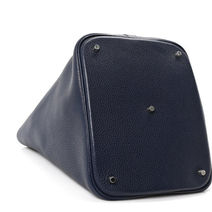 Navy leather tote bag with corner hardware and top handle loop, angled view