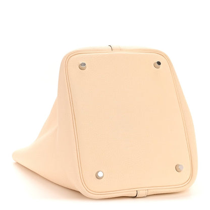 Light beige leather bucket bag with corner studs and foldover panel