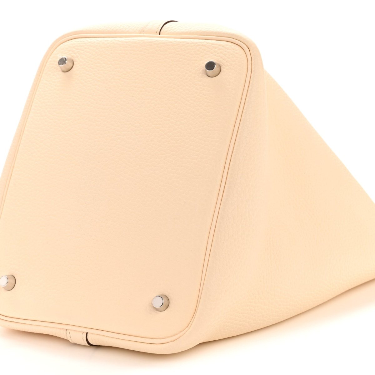 Light beige leather bucket bag bottom corner with metal stud and curved base