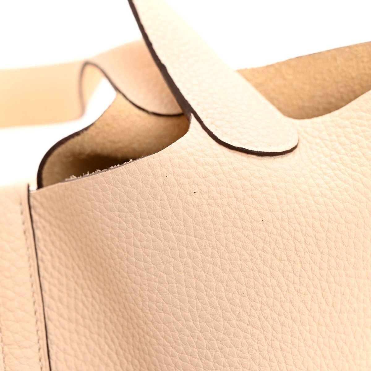 Cream leather bucket bag corner close-up with top edge and interior lining