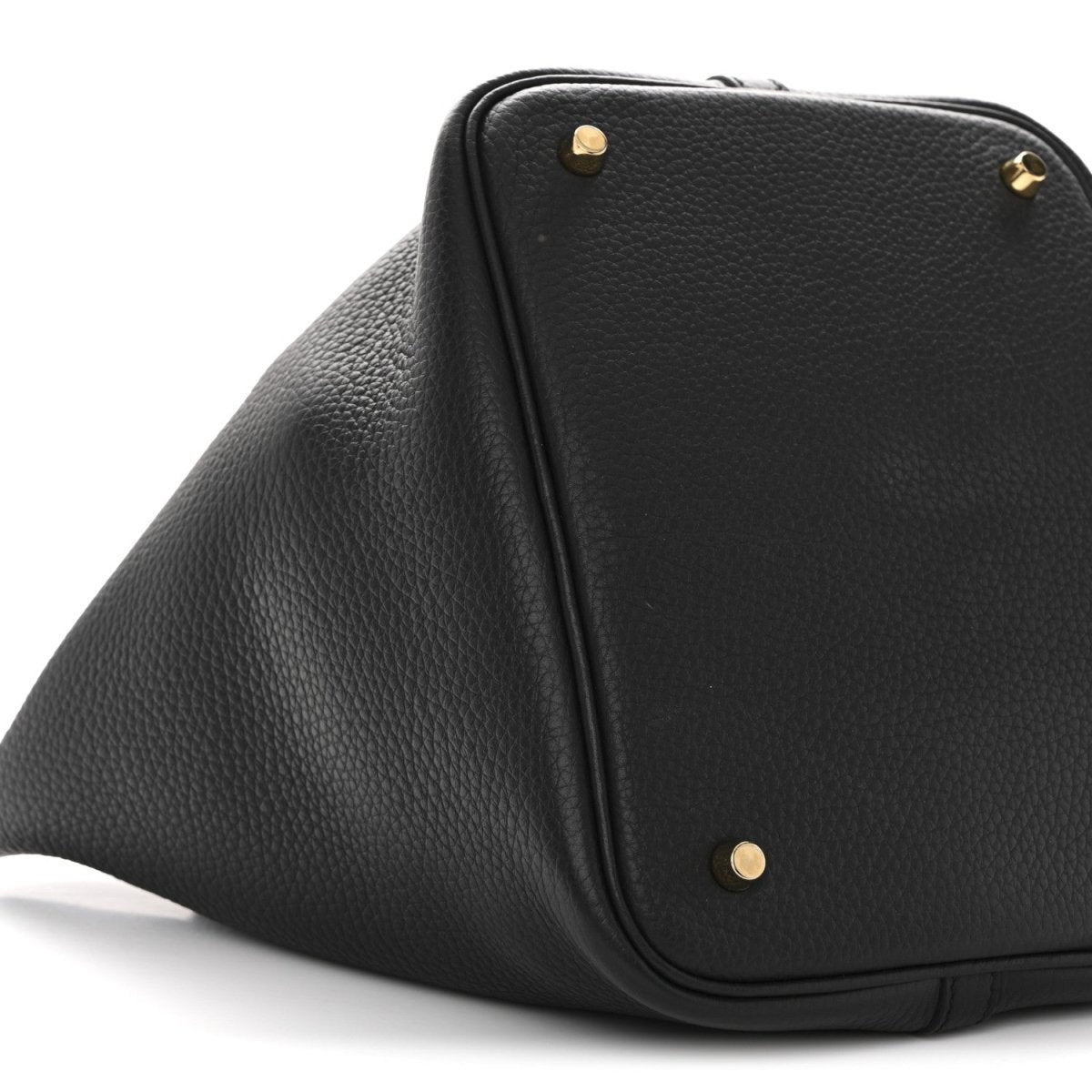Black leather tote bag corner with gold-tone studs and rounded top edge.