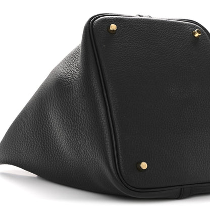 Black leather tote bag corner with gold-tone studs and rounded top edge.