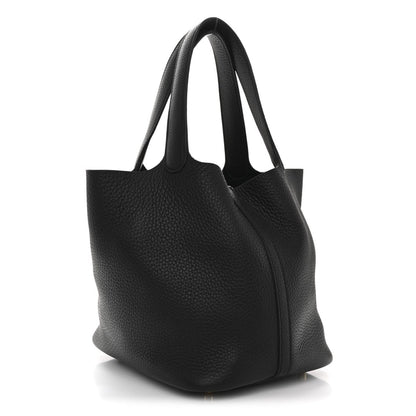 Black leather tote bag with textured grain, curved handles, and zip lock closure.