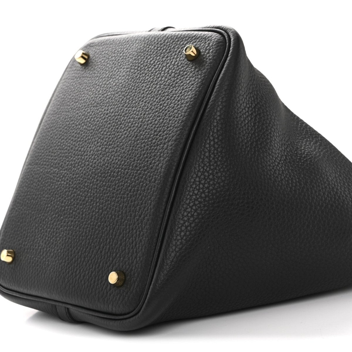 Black leather tote bag base corner with gold-tone studs and zip seam detail.