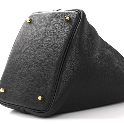 Black leather tote bag base corner with gold-tone studs and zip seam detail.
