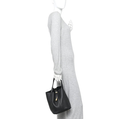Black leather tote bag worn crossbody, small size with zip lock and short handles.