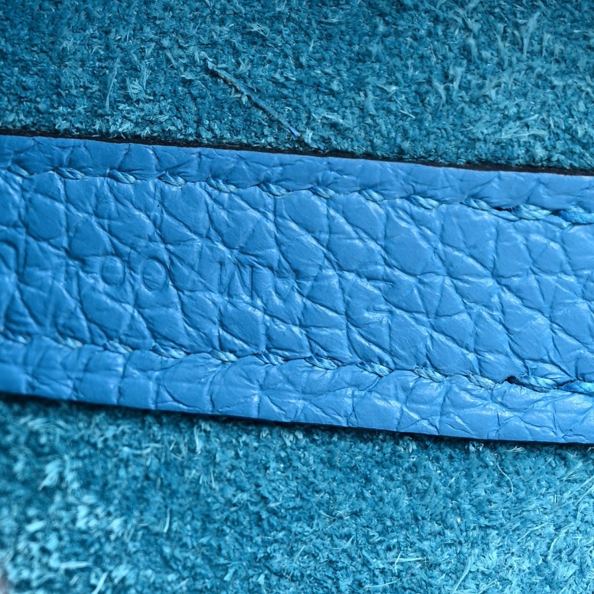 Blue pebbled leather panel close-up with stitched trim