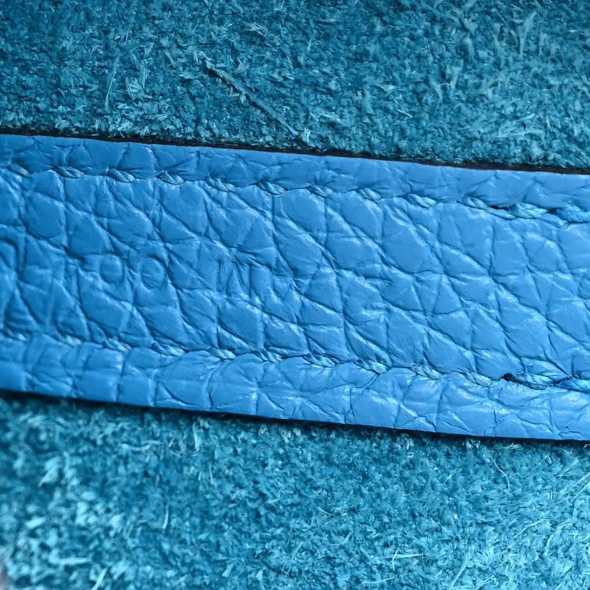 Blue pebbled leather panel close-up with stitched trim