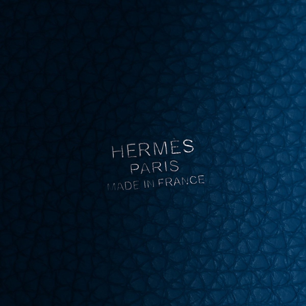 Blue leather close-up with embossed text: HERMES PARIS MADE IN FRANCE
