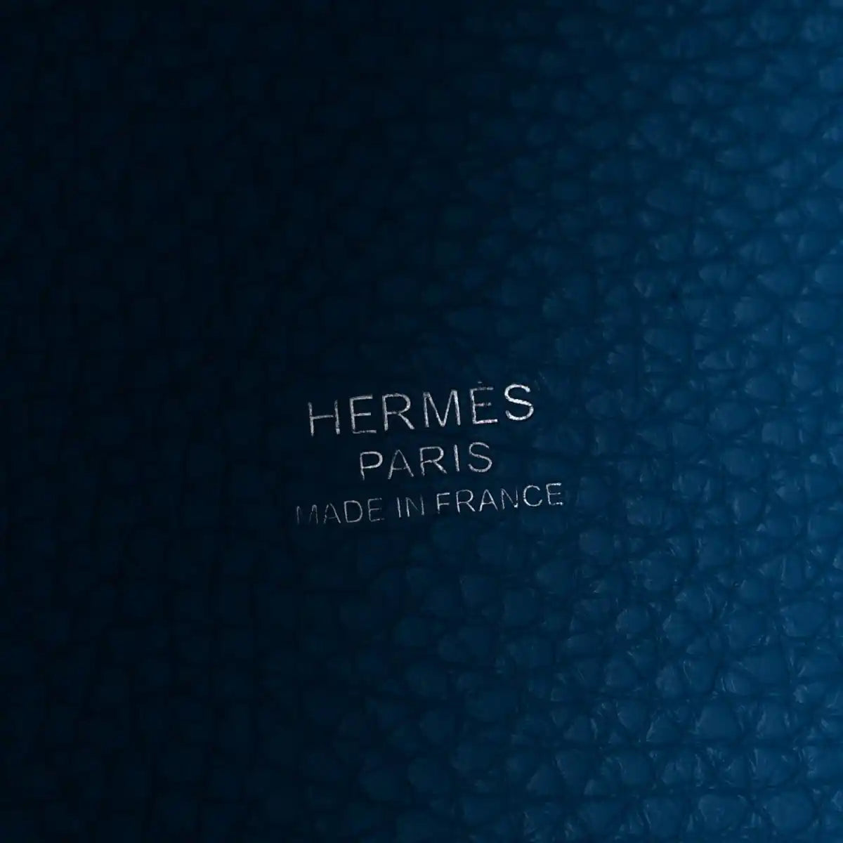 Blue leather close-up with embossed text: HERMES PARIS MADE IN FRANCE