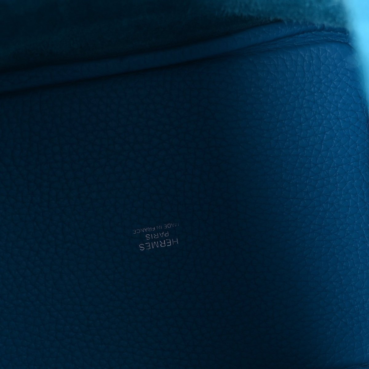 Blue pebbled leather close-up with textured grain and stitched edge
