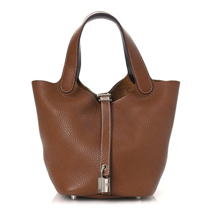 Brown leather tote bag with hinged front lock and top handles, gold-tone hardware
