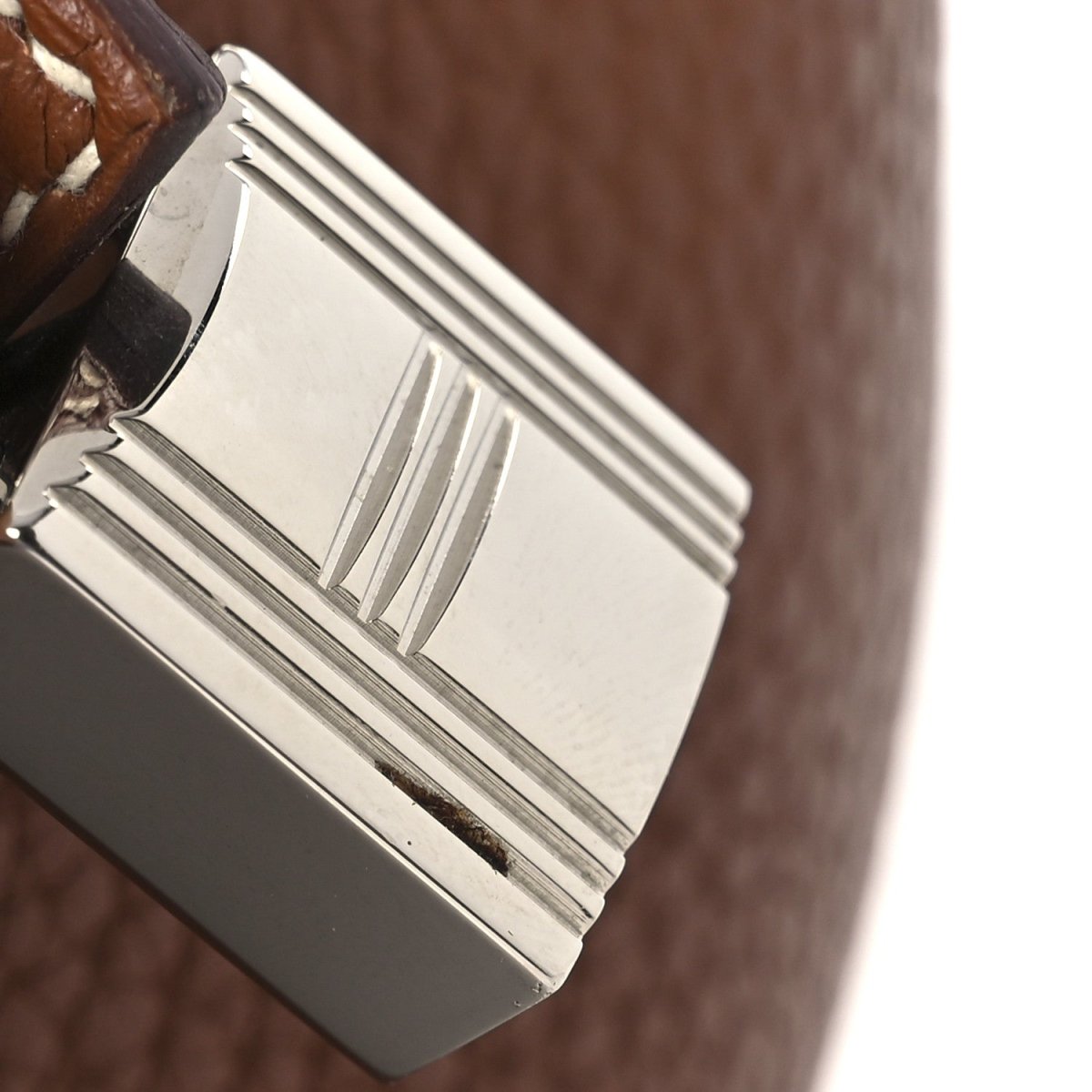 Silver-tone lock clasp and ridged side hardware on brown leather