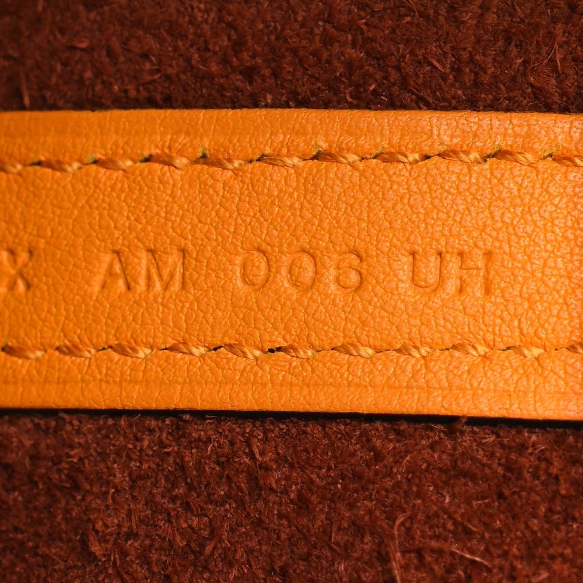 Tan leather strap with engraved 'AM 006 UN' and contrast stitching