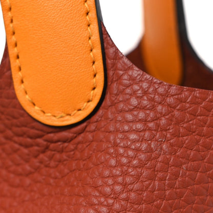 Red leather tote with copper-orange handle edge and contrast stitching