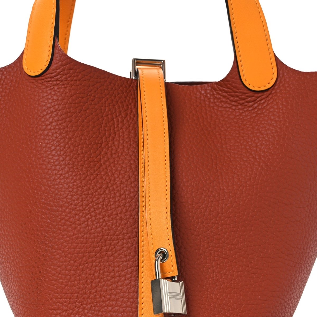 Copper-brown leather tote with tan vertical strap and silver lock hardware