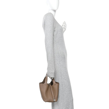 Beige leather bucket bag worn crossbody with short handle straps and side lock