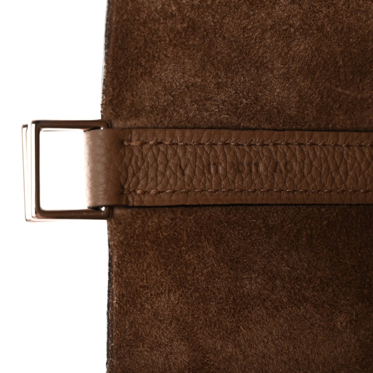 Beige leather bucket bag showing metal strap buckle and stitched leather edge