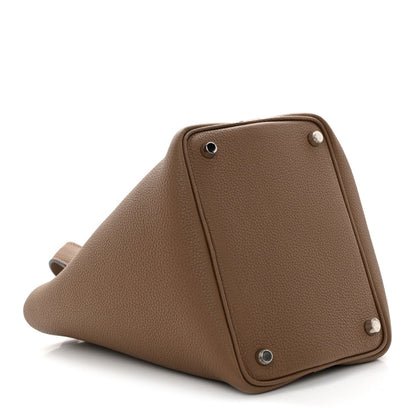 Beige leather bucket bag with studded corners and triangular side profile