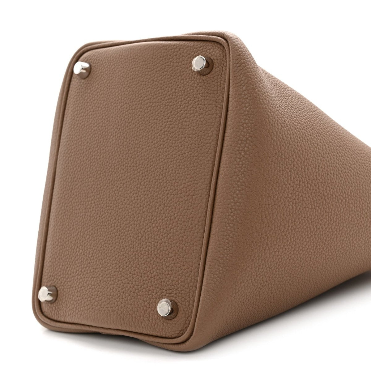 Beige leather bucket bag corner close-up with four metal studs and rounded base