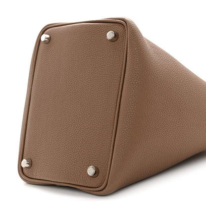 Beige leather bucket bag corner close-up with four metal studs and rounded base