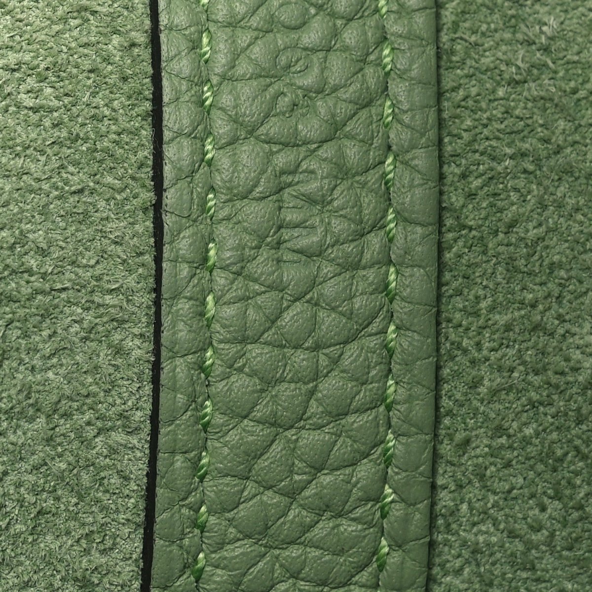 Green leather bag edge with stitched seam and textured grain
