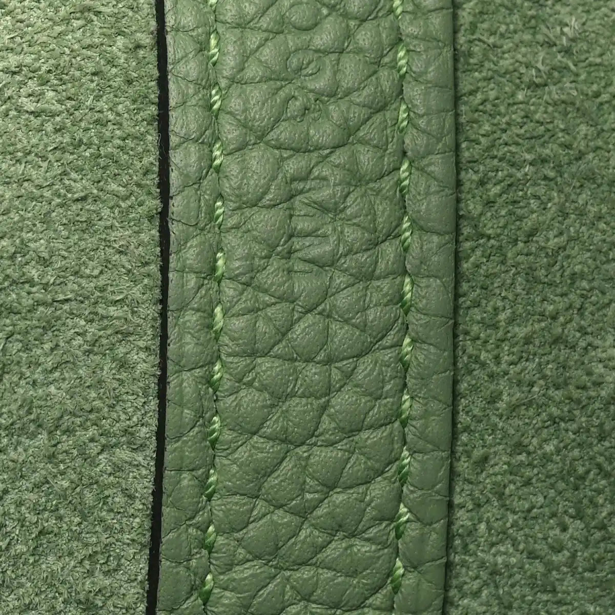 Green leather bag edge with stitched seam and textured grain