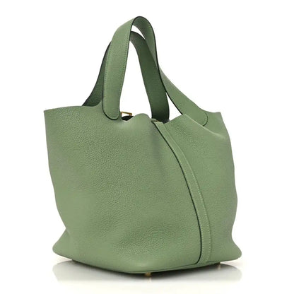 Green leather bucket bag with curved silhouette, top handles, and center seam