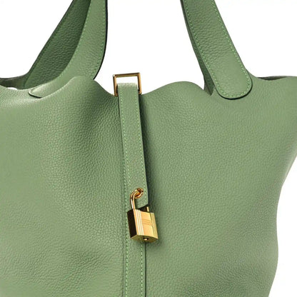 Green leather bucket bag front close-up with gold-tone lock and strap
