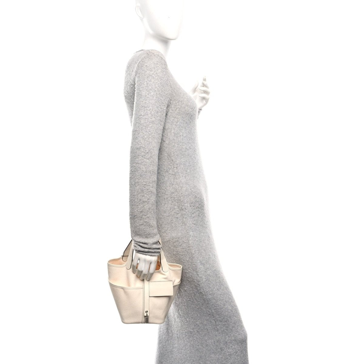 Cream canvas tote bag held at side with short handles and metal lock clasp