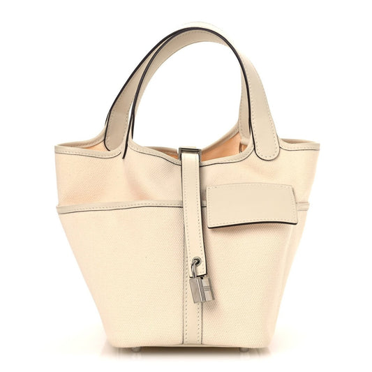 Cream canvas tote bag with top handles, front pocket, and metal lock clasp